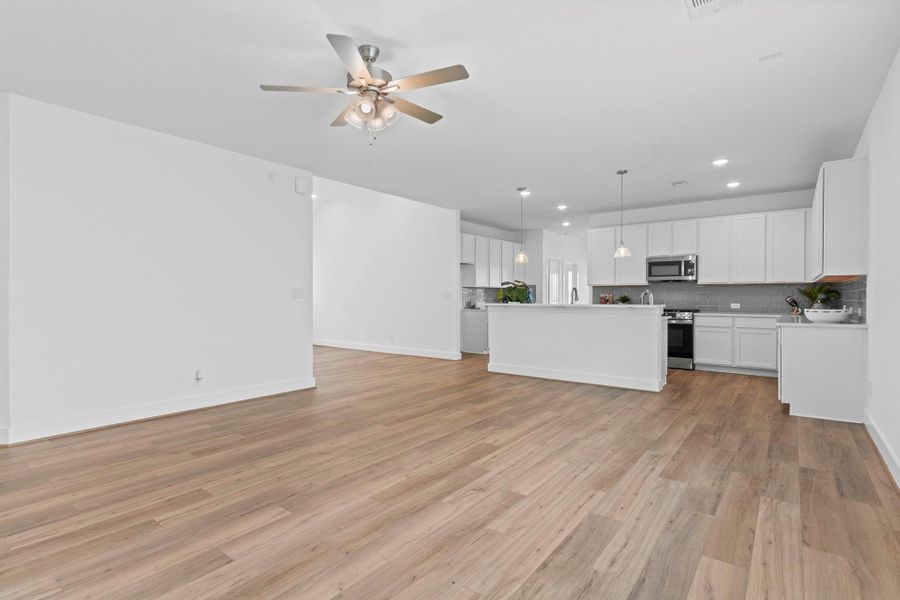 Spacious family room features large windows for natural light, recessed lighting, ceiling fan, and sleek flooring throughout. **Image Representative of Plan Only and May Vary as Built**.