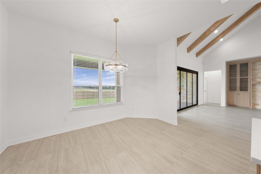 A well-lit dining area featuring a distinctive chandelier and exposed ceiling beams, with views of the outdoors. A well-lit dining area featuring a distinctive chandelier and exposed ceiling beams, with views of the outdoors.