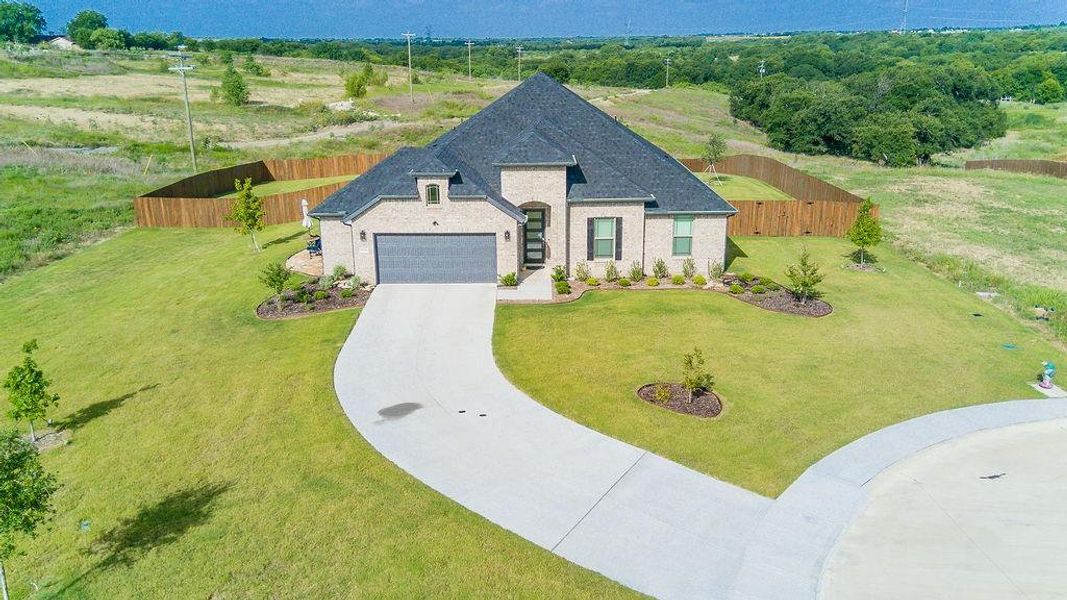 Spacious backyard featuring a wood pergola over a circular stone patio, raised garden beds, and a full privacy fence