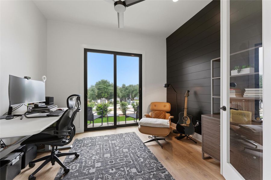 Room featuring light wood-finish flooring, a contemporary ceiling fan, and a contrasting dark shiplap accent wall Room featuring light wood-finish flooring, a contemporary ceiling fan, and a contrasting dark shiplap accent wall