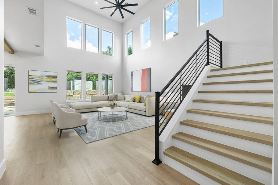 Living room featuring a towering ceiling, stairway, wood finished floors, and baseboards Living room featuring a towering ceiling, stairway, wood finished floors, and baseboards