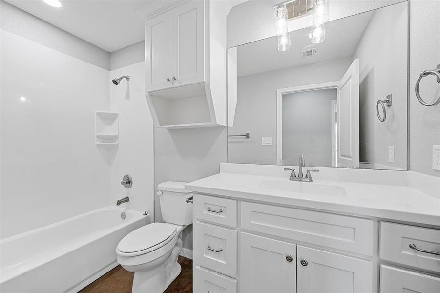 Full bathroom featuring vanity, toilet, visible vents, baseboards, and shower / washtub combination