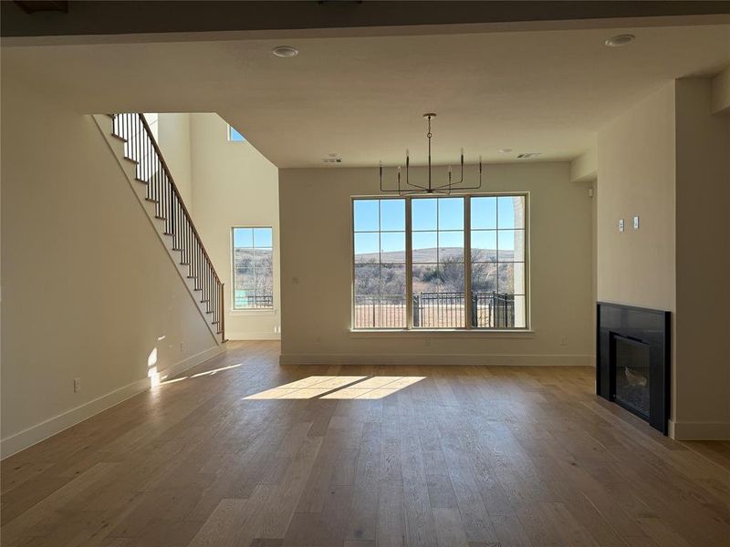 Unfurnished living room featuring an inviting chandelier, a wealth of natural light, a mountain view, and hardwood / wood-style floors