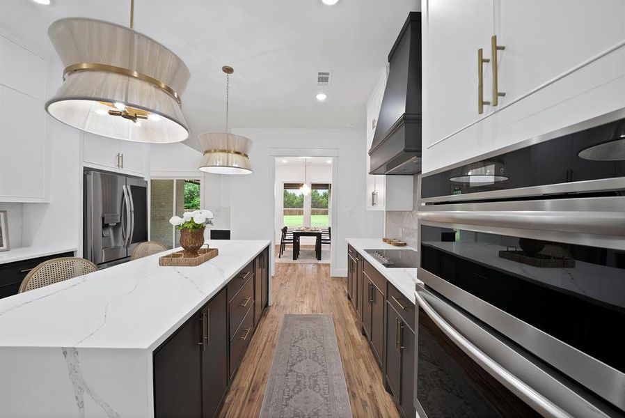 The kitchen features an expansive island with a white countertop, dark cabinetry, and integrated stainless steel appliances