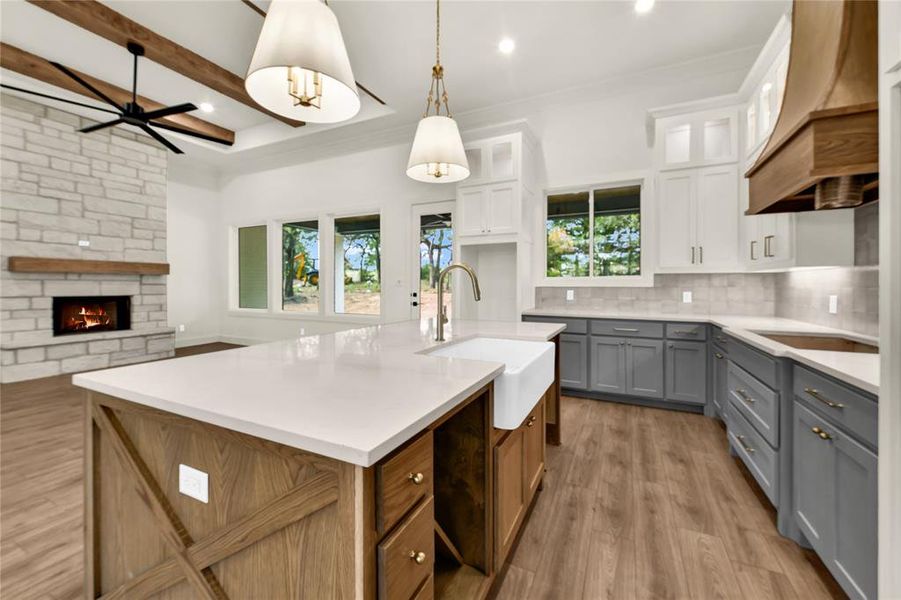 Kitchen featuring plenty of natural light, tasteful backsplash, light wood-style floors, a center island with sink, and beamed ceiling Kitchen featuring plenty of natural light, tasteful backsplash, light wood-style floors, a center island with sink, and beamed ceiling