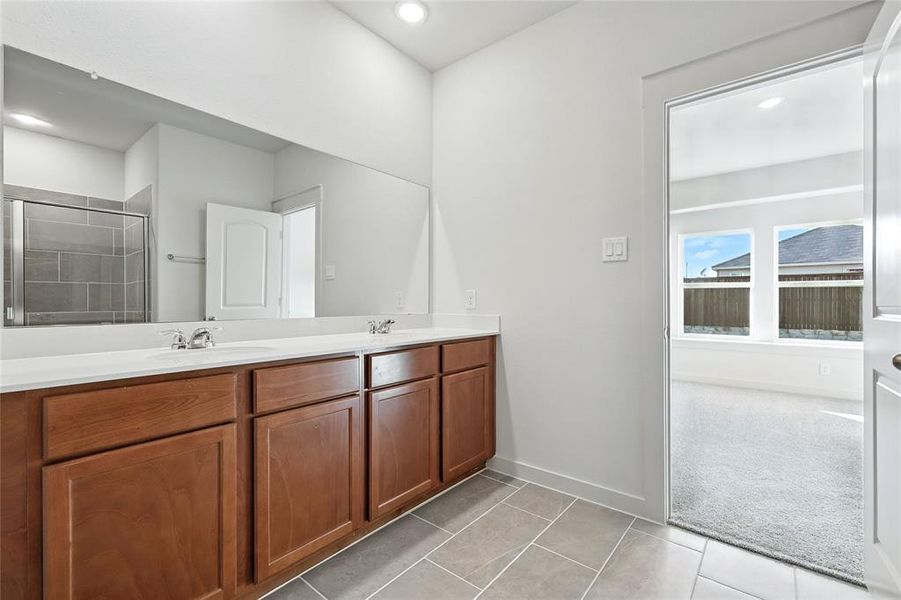Bathroom with double vanity, light tile patterned flooring, a shower stall, and recessed lighting Bathroom with double vanity, light tile patterned flooring, a shower stall, and recessed lighting