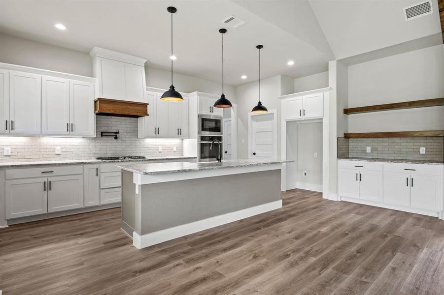 Kitchen featuring decorative backsplash, dark wood-style floors, pendant lighting, light stone counters, and recessed lighting Kitchen featuring decorative backsplash, dark wood-style floors, pendant lighting, light stone counters, and recessed lighting
