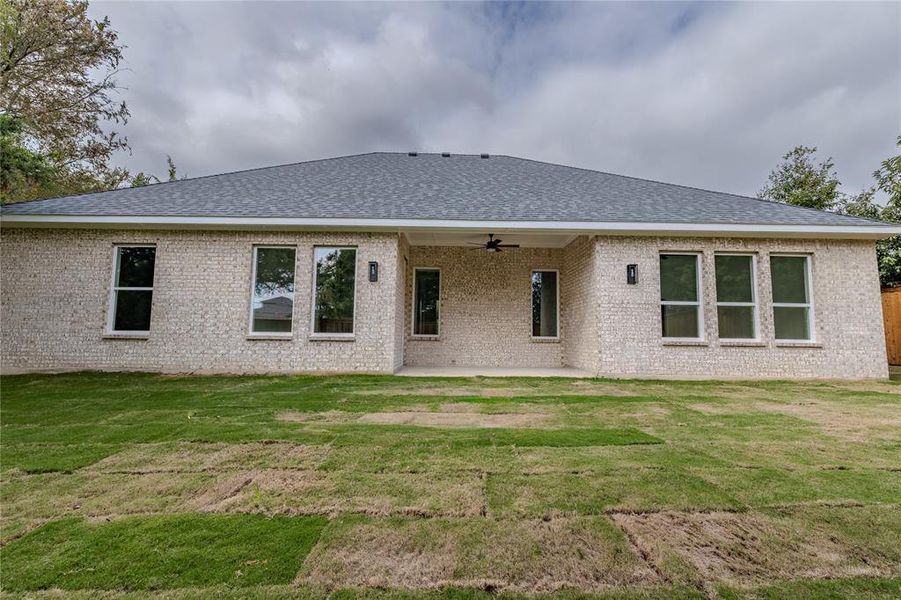 Back of property featuring a yard, a patio area, a ceiling fan, and roof with shingles