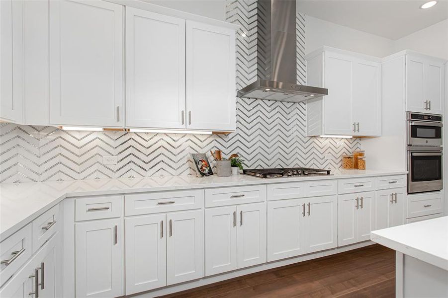 Kitchen featuring white cabinetry, stainless steel appliances, wall chimney exhaust hood, backsplash, and dark wood-type flooring