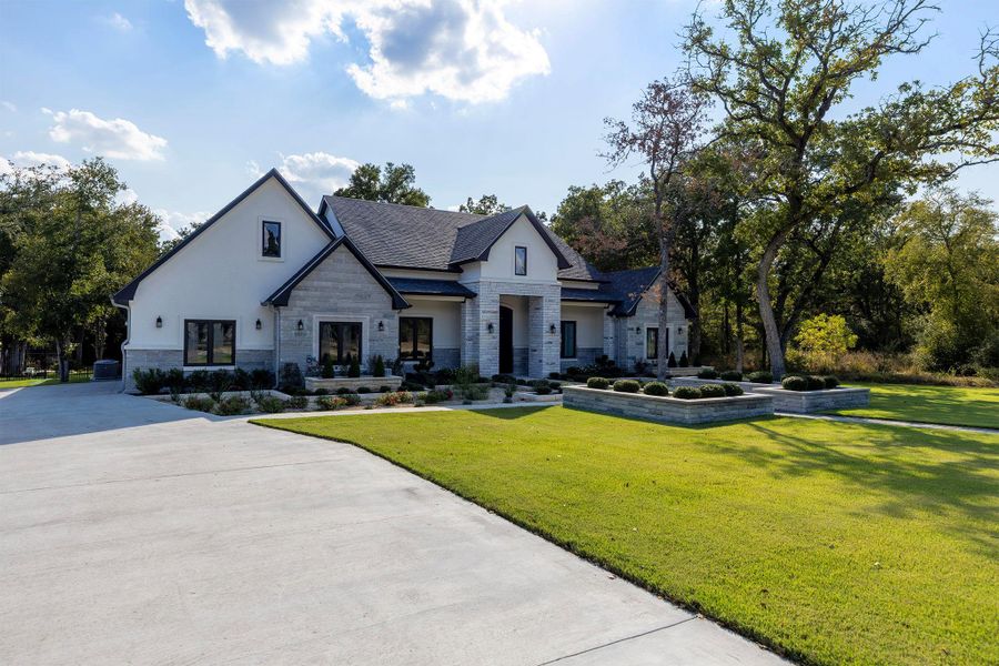 Modern farmhouse style home featuring a front yard and stone siding Modern farmhouse style home featuring a front yard and stone siding