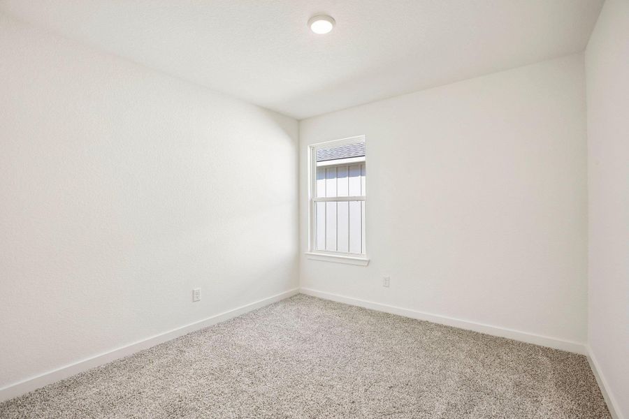 Soft carpeting pairs with neutral walls and a central window in this versatile bedroom.