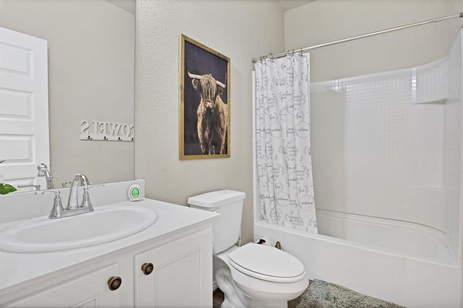 Full bathroom with vanity, toilet, and shower / bath combo with shower curtain