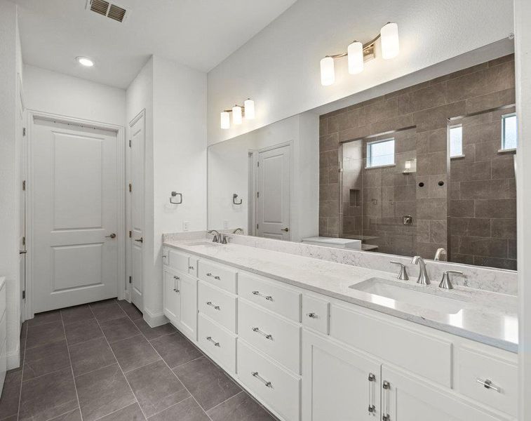 Bathroom featuring double vanity, visible vents, walk in shower, and a sink