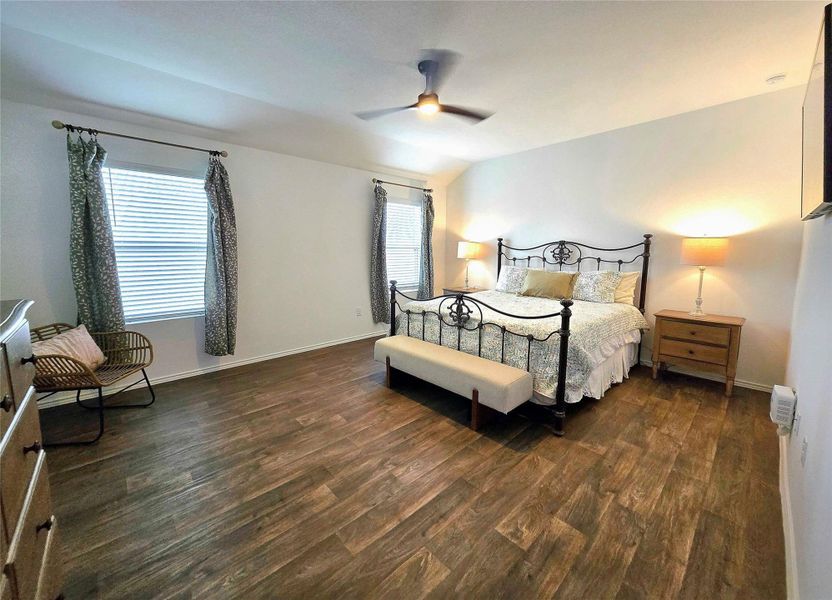Spacious room featuring wood-finish flooring, white walls, and two large windows with blinds