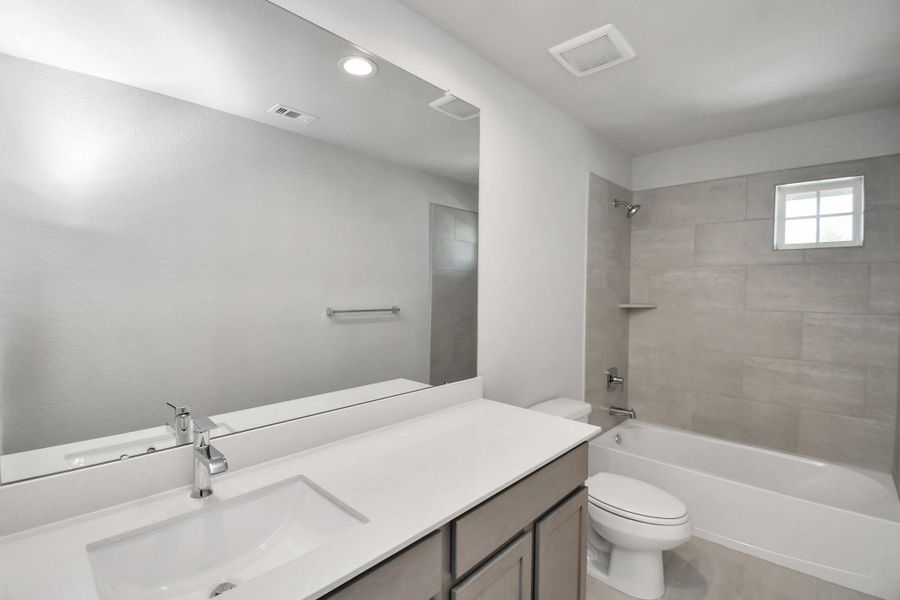 Secondary bath features tile flooring, bath/shower combo with tile surround, light stained wood cabinets, beautiful light countertop. Sample photo of completed home with similar floor plan. Actual colors and selections may vary. Secondary bath features tile flooring, bath/shower combo with tile surround, light stained wood cabinets, beautiful light countertop. Sample photo of completed home with similar floor plan. Actual colors and selections may vary.