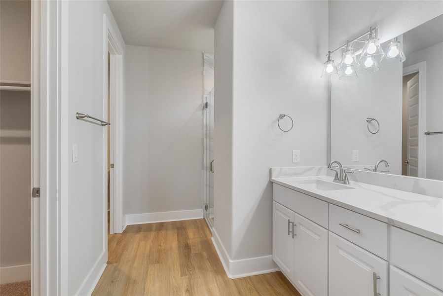 Primary bath featuring dual vanity, quartz countertops, modern fixtures, large walk in closet, and floor-to-ceiling shower tile Primary bath featuring dual vanity, quartz countertops, modern fixtures, large walk in closet, and floor-to-ceiling shower tile