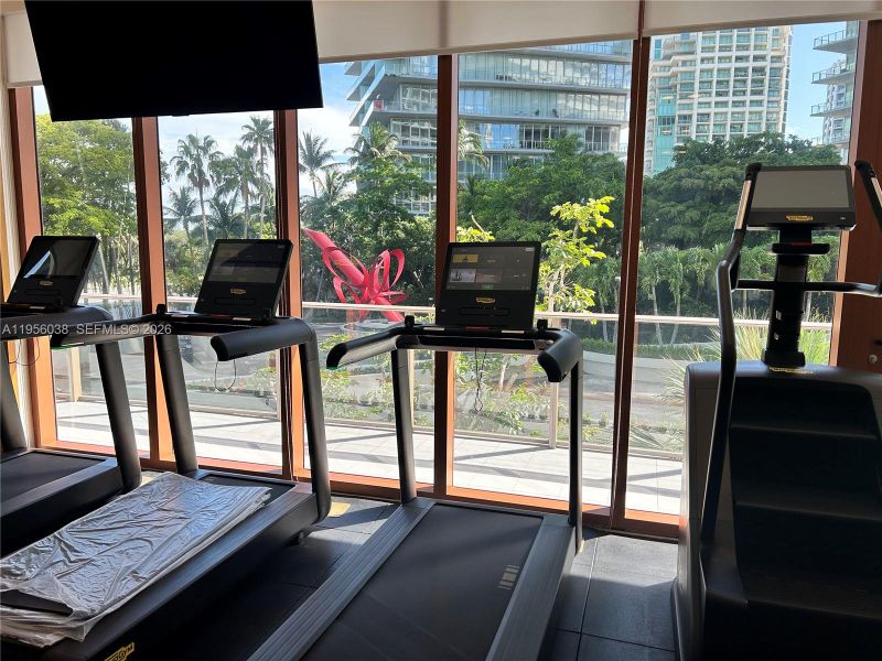 Modern fitness center with premium equipment, floor-to-ceiling windows, and tranquil views—designed for wellness and performance.