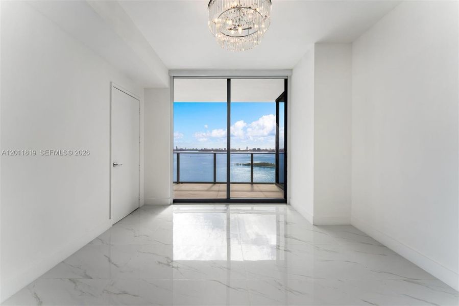 Serene primary suite offering unobstructed water views, direct terrace access, oversized walk-in closets, and floor-to-ceiling windows for a true 'mansion in the sky' feel.