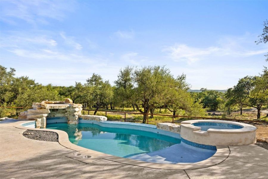 An inviting private pool and spa await, complemented by a rock waterfall and serene natural surroundings. An inviting private pool and spa await, complemented by a rock waterfall and serene natural surroundings.