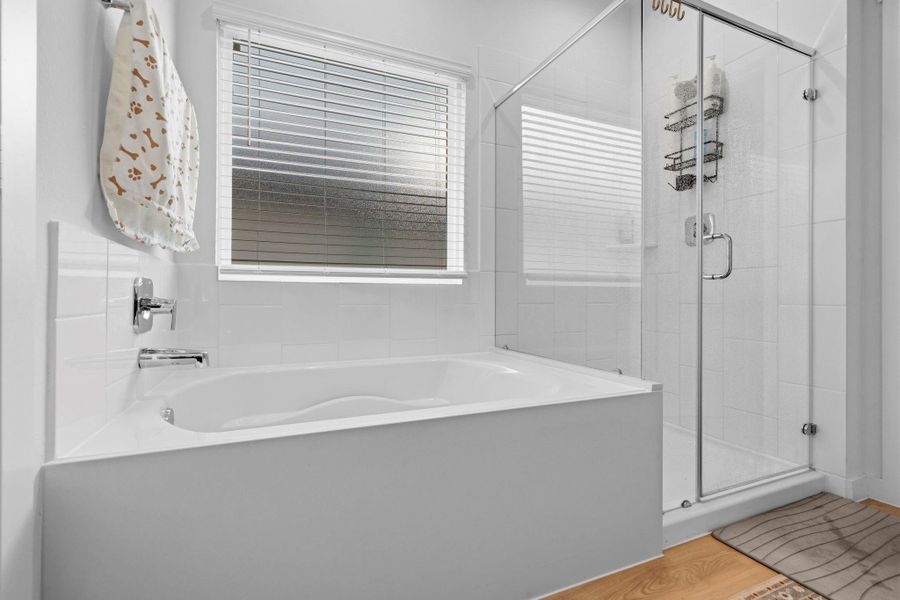Modern bathroom with a glass-enclosed shower and deep soaking tub. Bright white tile, chrome fixtures, and a frosted window provide natural light with privacy, creating a clean, spa-like feel. Modern bathroom with a glass-enclosed shower and deep soaking tub. Bright white tile, chrome fixtures, and a frosted window provide natural light with privacy, creating a clean, spa-like feel.