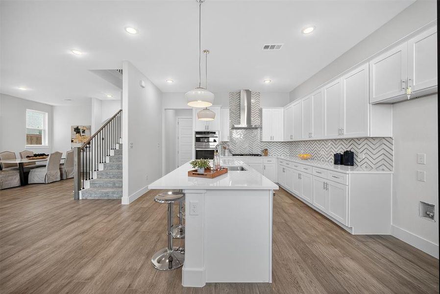 Kitchen featuring backsplash, white cabinets, hanging light fixtures, dark wood-style flooring, and recessed lighting Kitchen featuring backsplash, white cabinets, hanging light fixtures, dark wood-style flooring, and recessed lighting