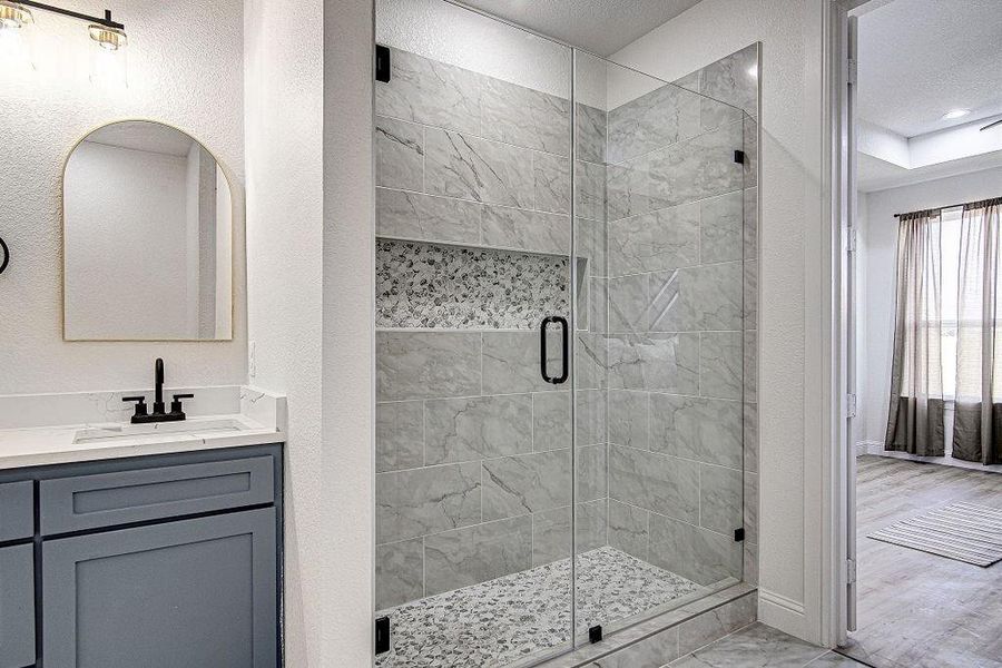 Bathroom with a stall shower, vanity, and a textured wall