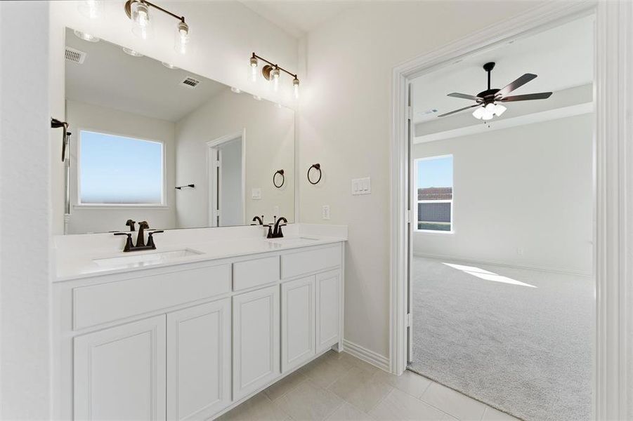 Full bathroom featuring light tile patterned floors, double vanity, light colored carpet, and a ceiling fan