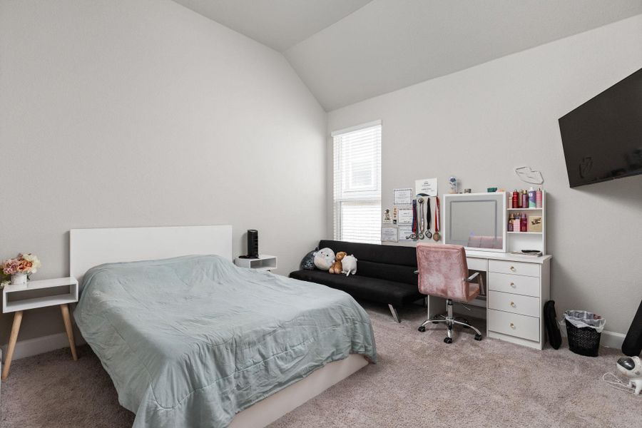 Carpeted bedroom featuring vaulted ceiling and baseboards