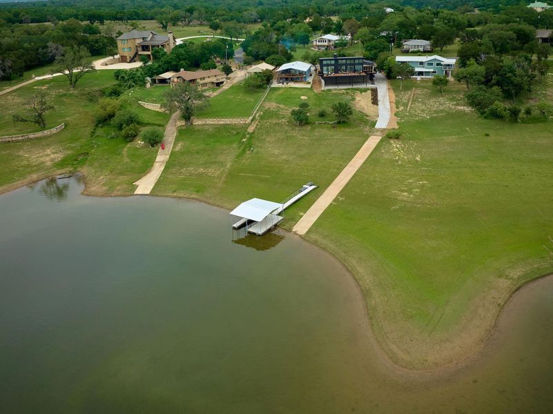 Lakeside property featuring a private boat dock with covered slip and a concrete boat ramp
