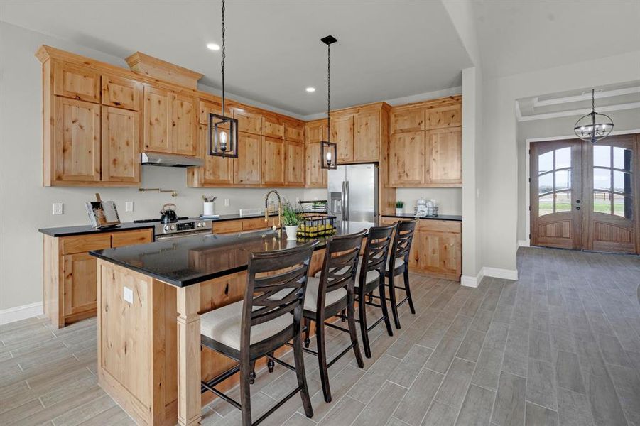 Kitchen with a kitchen breakfast bar, an inviting chandelier, a center island with sink, hanging light fixtures, and stainless steel appliances