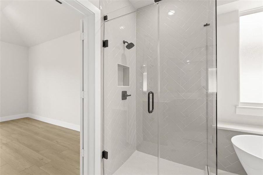 Bathroom with baseboards, a freestanding bath, a stall shower, and wood finished floors