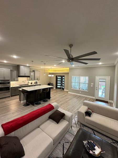 Living room featuring light wood-style flooring, recessed lighting, ornamental molding, and ceiling fan