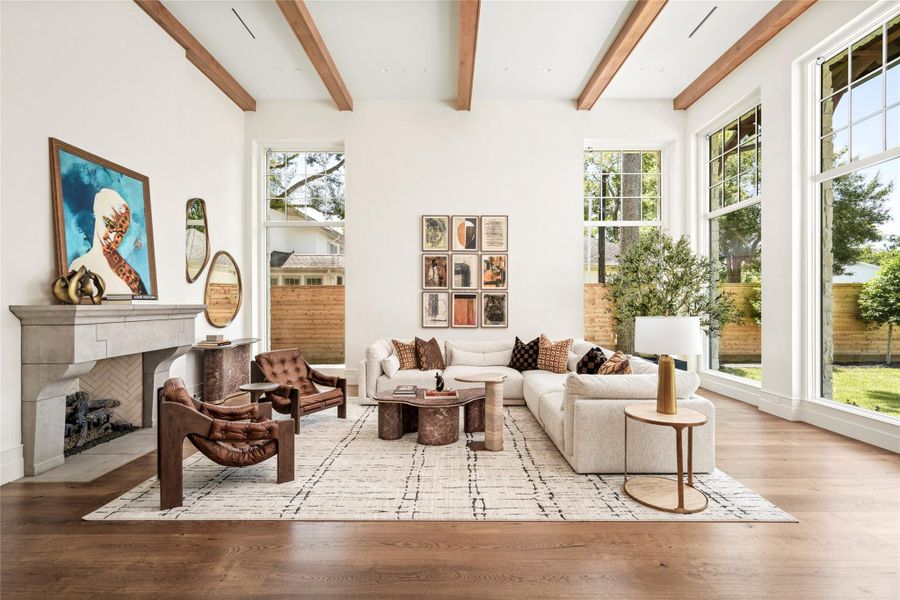 The great room is defined by soaring ceilings, warm alder beams, and expansive windows that flood the space with natural light and frame views of the backyard. A hand-carved limestone fireplace and wide-plank white oak flooring bring warmth and timeless character to the space. The great room is defined by soaring ceilings, warm alder beams, and expansive windows that flood the space with natural light and frame views of the backyard. A hand-carved limestone fireplace and wide-plank white oak flooring bring warmth and timeless character to the space.