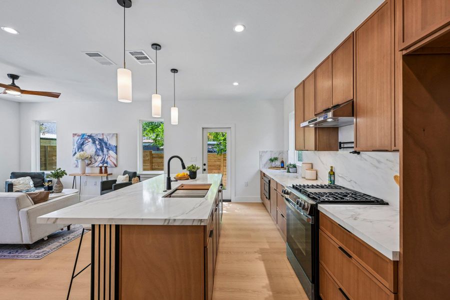 Well-lit kitchen with a gas range and a bright living area, perfect for entertaining. Well-lit kitchen with a gas range and a bright living area, perfect for entertaining.
