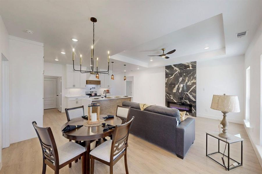 Dining area featuring a raised ceiling, light hardwood / wood-style floors, and ceiling fan