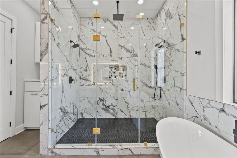 The oversized walk-in shower features multiple showerheads, including a soothing rain shower, with porcelain tile carried all the way to the ceiling — pure spa-level luxury.