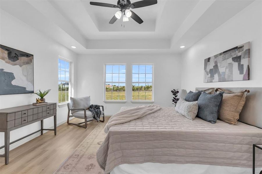 Bedroom featuring light wood-style floors, a ceiling fan, a tray ceiling, and recessed lighting Bedroom featuring light wood-style floors, a ceiling fan, a tray ceiling, and recessed lighting