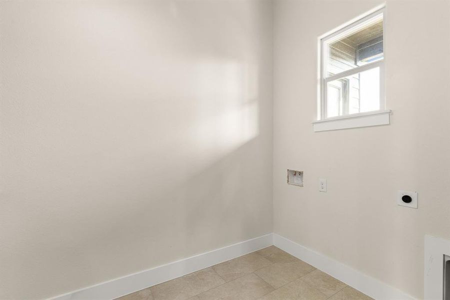 Washroom with light tile patterned floors, hookup for a washing machine, hookup for an electric dryer, laundry area, and baseboards