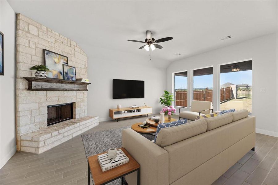 Living area with a stone fireplace, wood finish floors, and ceiling fan Living area with a stone fireplace, wood finish floors, and ceiling fan