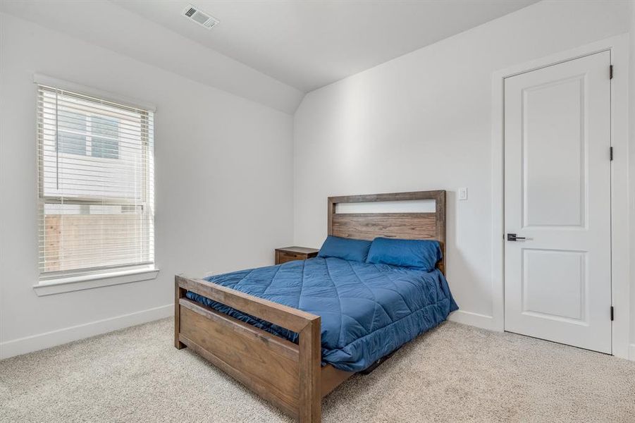 Bedroom with light colored carpet and lofted ceiling