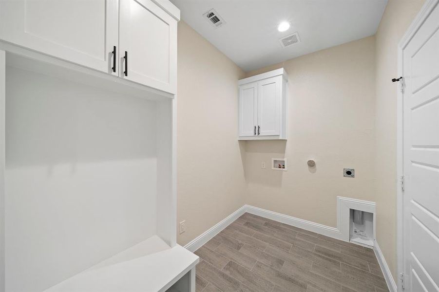 Washroom featuring hookup for a washing machine, cabinets, hookup for an electric dryer, light hardwood / wood-style flooring, and hookup for a gas dryer