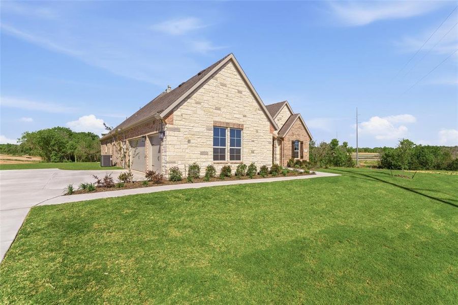 View of front of home with a front yard, stone siding, and concrete driveway