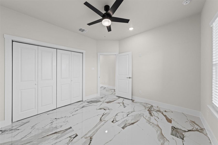 Polished stone-look tile flooring complements the clean, neutral walls in this versatile bedroom.