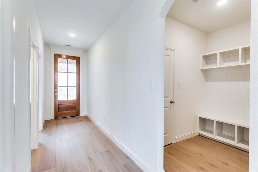 Mudroom featuring light wood finished floors, arched walkways, baseboards, and recessed lighting