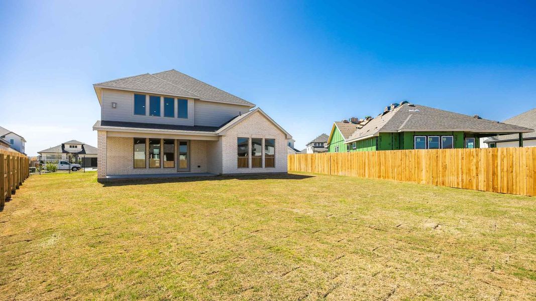 Back of house with brick siding, a fenced backyard, and a yard Back of house with brick siding, a fenced backyard, and a yard