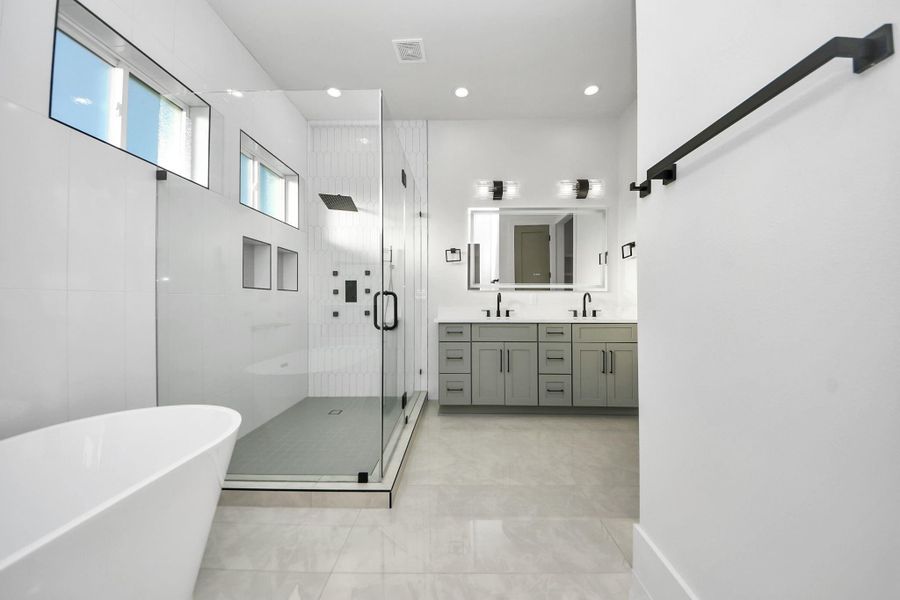 Step into the luxurious primary suite, a true spa-like retreat. The 24x48 large tile flooring flows seamlessly, complemented by elegantly tiled accent walls in the shower. Double vanities with separate drawers offer ample storage, blending beauty and practicality. Step into the luxurious primary suite, a true spa-like retreat. The 24x48 large tile flooring flows seamlessly, complemented by elegantly tiled accent walls in the shower. Double vanities with separate drawers offer ample storage, blending beauty and practicality.