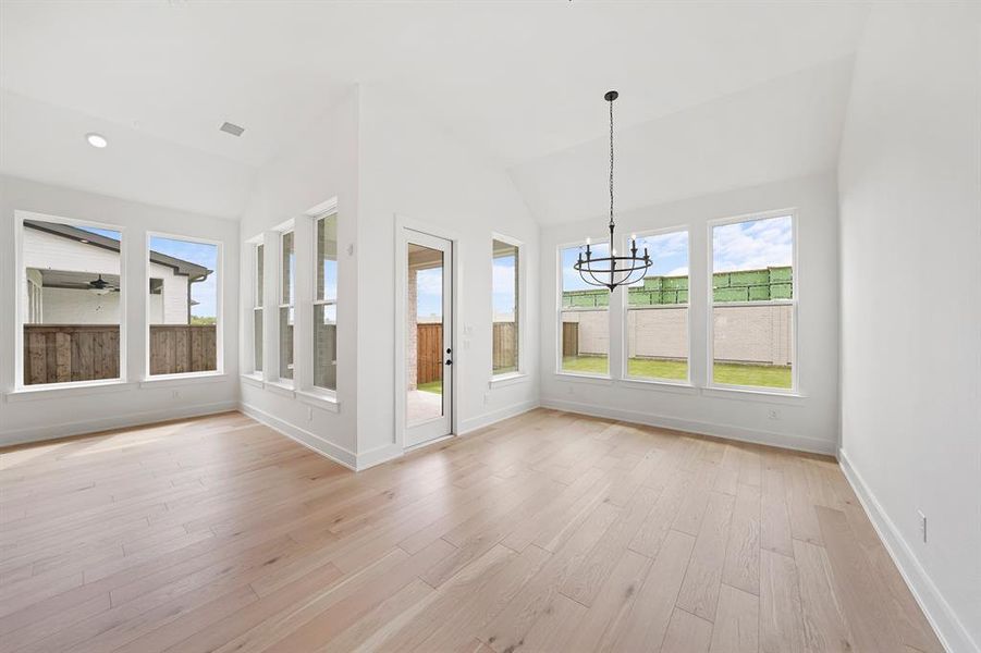 Unfurnished sunroom with wood finished floors, lofted ceiling, and a chandelier Unfurnished sunroom with wood finished floors, lofted ceiling, and a chandelier