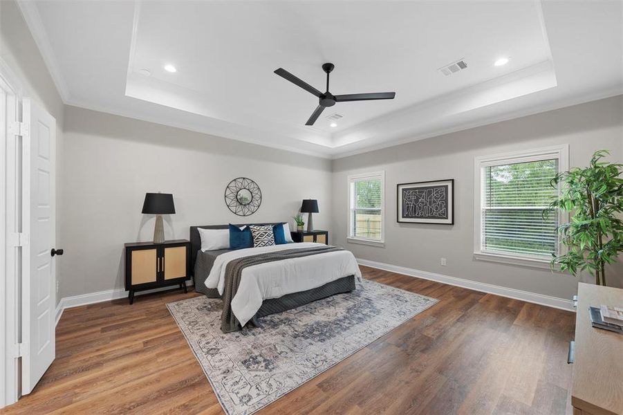 Bedroom featuring visible vents, ornamental molding, wood finished floors, and a raised ceiling