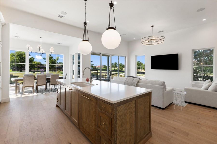 An open-concept living space with polished wood flooring transitions seamlessly from kitchen to dining area, illuminated by bright windows and contemporary lighting. An open-concept living space with polished wood flooring transitions seamlessly from kitchen to dining area, illuminated by bright windows and contemporary lighting.