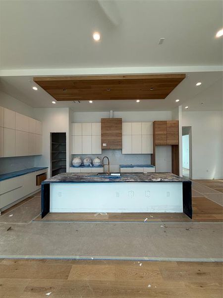 Kitchen featuring backsplash, a spacious island, modern cabinets, recessed lighting, and wood finished floors Kitchen featuring backsplash, a spacious island, modern cabinets, recessed lighting, and wood finished floors